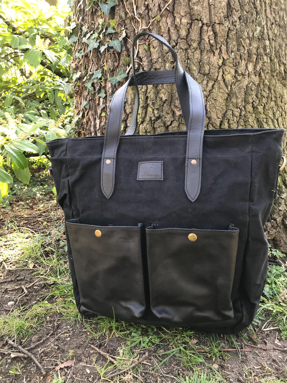 The Bingham.  A large zipped tote bag by Burghley Bags.  Handmade from eco-friendly vegetable tanned leather and strong cotton canvas, with a canvas shoulder strap. Shown in elegant black.