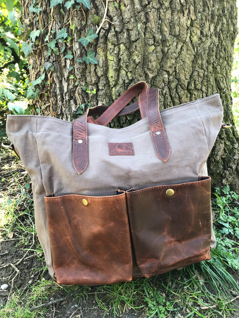 The Bingham.  A large zipped tote bag by Burghley Bags.  Handmade from eco-friendly vegetable tanned leather and strong cotton canvas, with a canvas shoulder strap. Shown in soft grey.