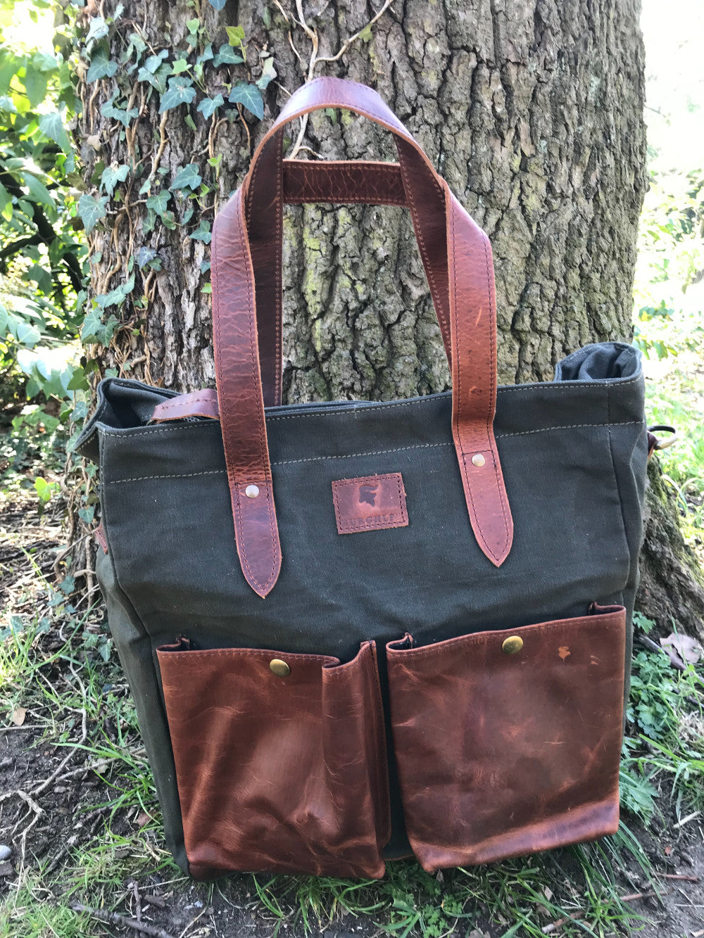 The Bingham.  A large zipped tote bag by Burghley Bags.  Handmade from eco-friendly vegetable tanned leather and strong cotton canvas, with a canvas shoulder strap. Shown in khaki green.