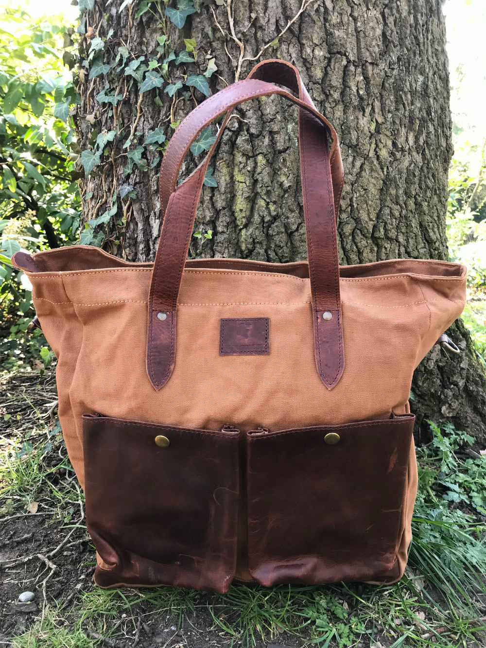 The Blenheim.  A large zipped tote bag by Burghley Bags.  Handmade from eco-friendly vegetable tanned leather and strong cotton canvas, with a canvas shoulder strap. Shown in classic tan.